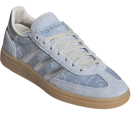 Adidas Handball Spezial sneaker in light blue suede with tonal three stripes, subtle patterned panels, metallic silver accents, and a classic gum rubber sole for a retro-inspired look.