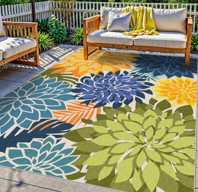 Colorful outdoor rug featuring oversized floral patterns in blue, green, and yellow, styled on a patio seating area.