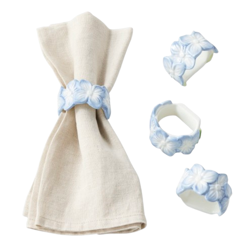 Set of four white napkin rings with raised blue hydrangea flower details, shown with a folded natural linen napkin.