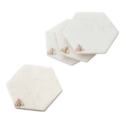Set of four white marble hexagon coasters with engraved honeycomb pattern and small gold bee accents.
