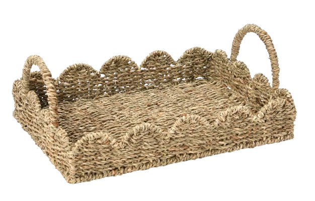 Natural woven seagrass serving tray with scalloped edges and curved handles, designed for casual entertaining, coffee table styling, or serving drinks outdoors.