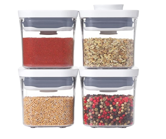 OXO Good Grips POP container set with four clear airtight storage containers filled with spices, mustard seeds, fennel seeds, and mixed peppercorns.