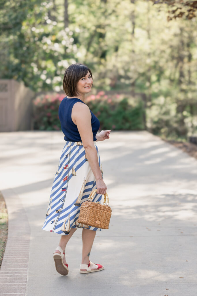 Navy sleeveless top with sailboat print skirt, wicker handbag and canvas espadrilles for nautical Americana style
