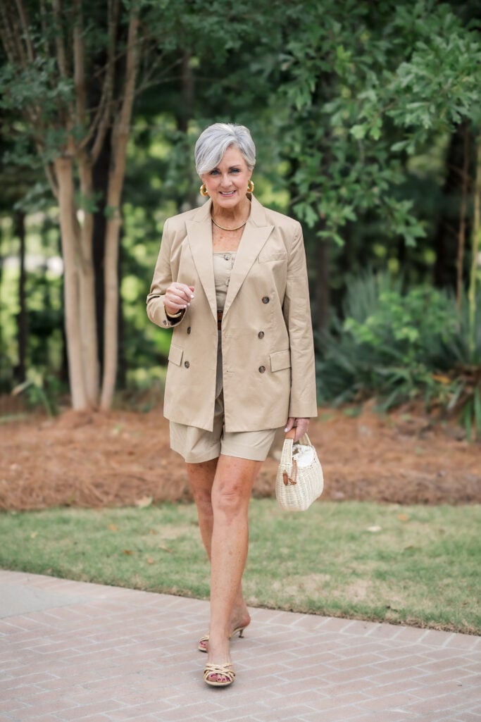 Khaki short suit with a double-breasted blazer, leather belt, raffia sandals, and wicker bag