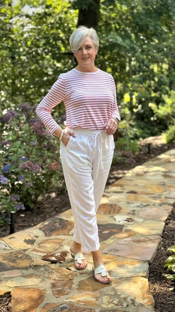 Woman over 50 wearing a striped three-quarter-sleeve tee with white linen pants