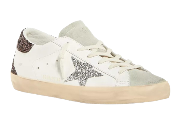 White leather Golden Goose Superstar sneakers featuring silver glitter star accents, distressed detailing, suede trim, and cream-colored rubber soles.