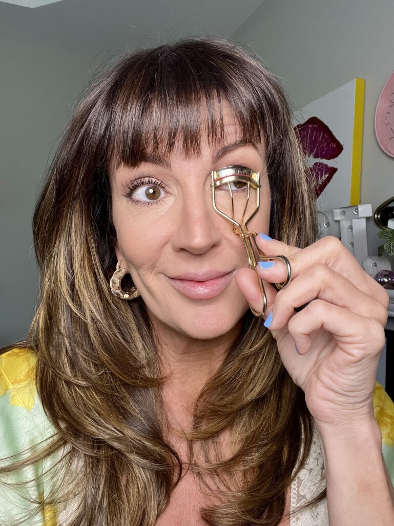 Hand holding a Shiseido eyelash curler to lift lashes after 50