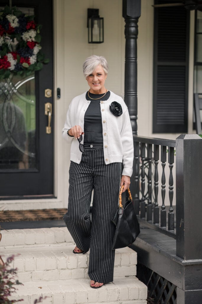 Beth Djalali in a black tee and black pinstripe wide-leg pants lifted with an ivory cardigan and gold collar necklace
