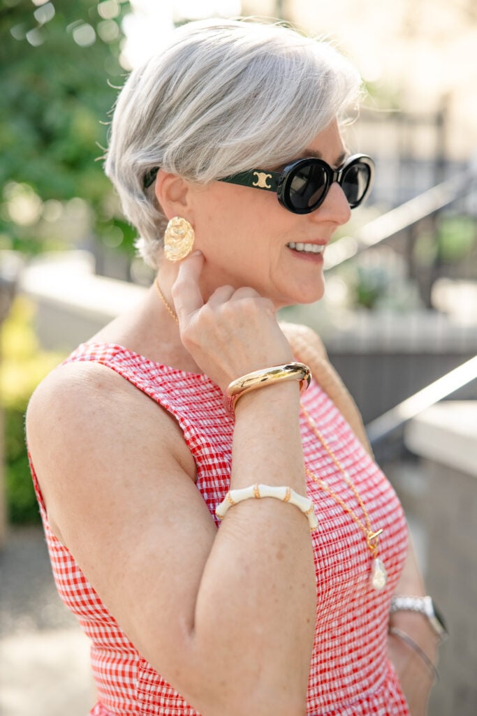 Gold pearl pendant necklace and wavey cuff bracelet styled with a red gingham summer dress