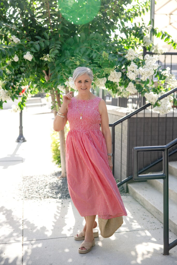 Beth Djalali in a red gingham smocked cotton midi dress with platform espadrilles and straw tote — a balanced summer dress look for women over 50