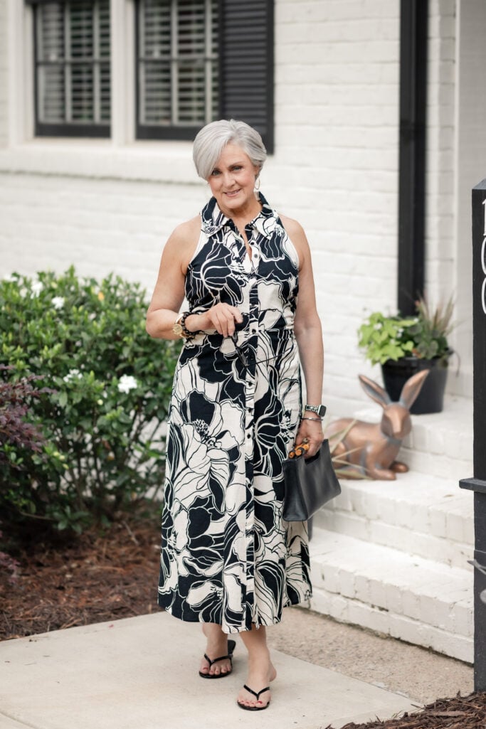 Beth wearing a sleeveless black and cream floral maxi shirtdress with black sandals