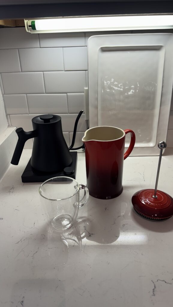 Red Le Creuset French press and Stagg gooseneck kettle styled on an apartment coffee station