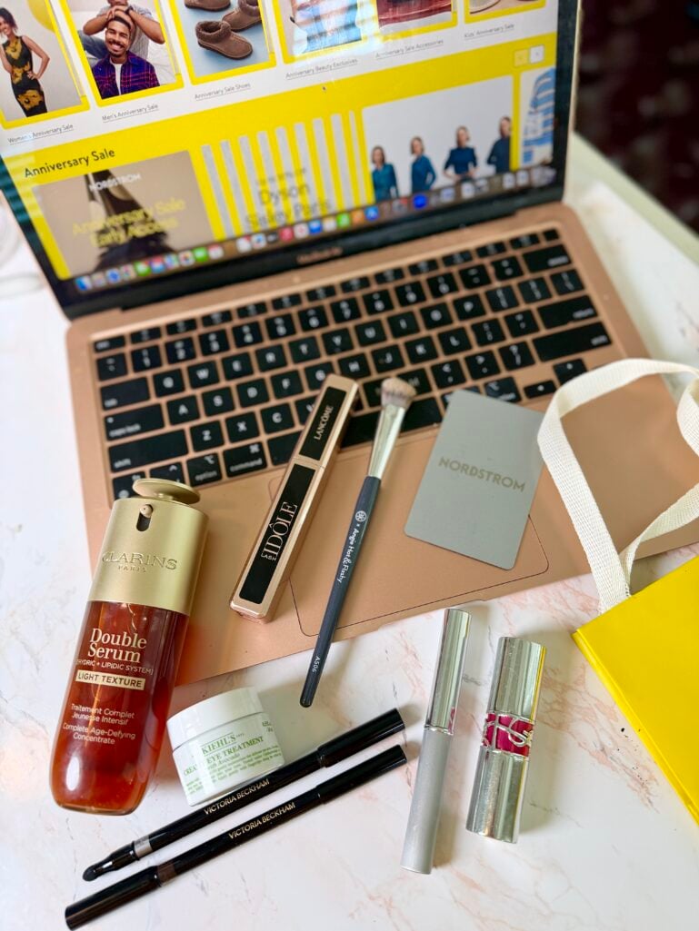 Flatlay of luxury beauty products from the Nordstrom Anniversary Sale beside a laptop