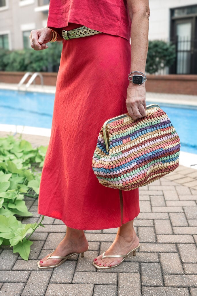 Close-up of coral Gap linen outfit with gold belt, statement earrings, and Warby Parker sunglasses