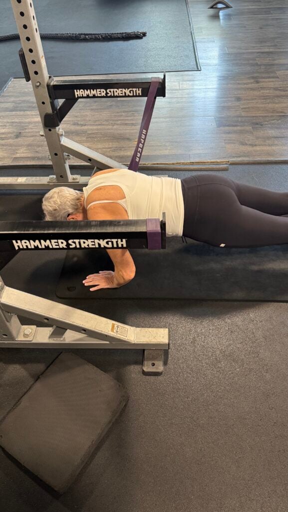 Beth Djalali performing a plank exercise with a resistance band during personal training at Fitness Together